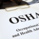 A close-up of a white paper attached to a clipboard that reads "OSHA" and "Occupational Safety and Health Administration."