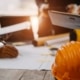 A close-up of an orange hard hat on a wooden table with people having a meeting with documents in the background.