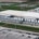 An aerial view of a large data center campus during the day with numerous cooling units, grass fields, and parking lots.