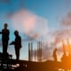 A silhouette of a construction site scaffolding with workers standing on platforms as the sun sets behind them.