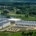 An aerial view of a large data center with solar panels on the roof, with residential houses in the background.