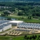 An aerial view of a large data center with solar panels on the roof, with residential houses in the background.